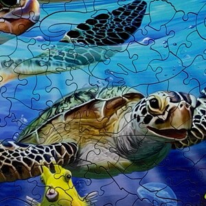 May include: A completed jigsaw puzzle featuring sea turtles swimming underwater. The puzzle pieces are interlocked, depicting turtles with patterned shells, surrounded by blue water and yellow fish. The image is a close-up view.