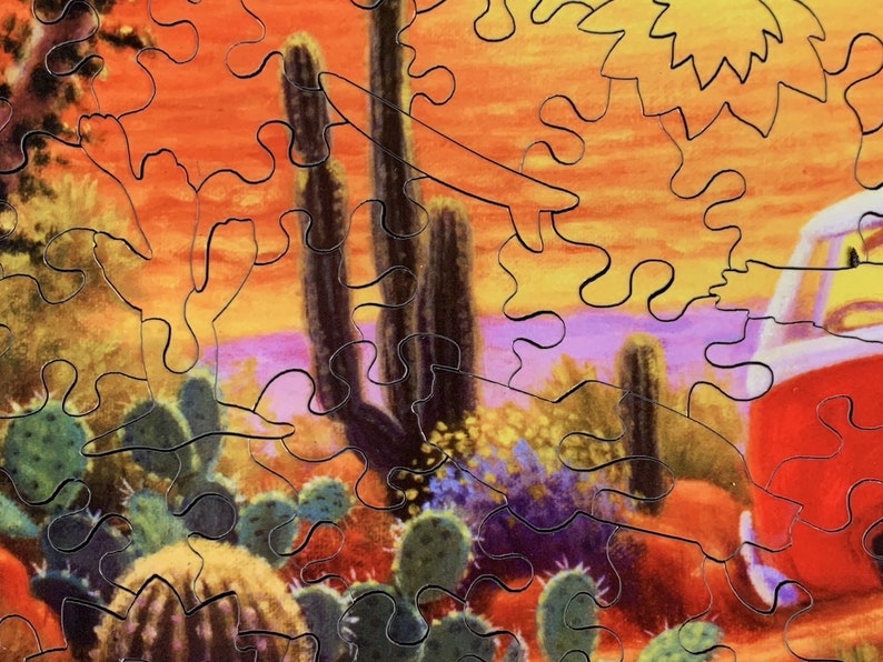 May include: A jigsaw puzzle depicting a desert landscape with cacti, a red vehicle, and a vibrant sunset. The puzzle pieces interlock to form a colorful scene with shades of orange, purple, and green, evoking a sense of adventure.