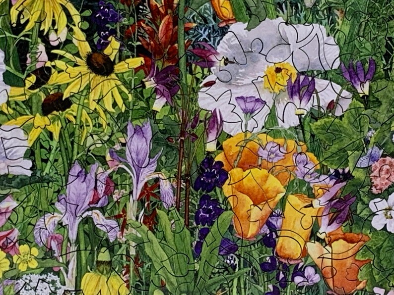 May include: A colorful jigsaw puzzle featuring a vibrant garden scene. The image showcases a variety of flowers, including yellow coneflowers, purple irises, and orange poppies, set against a backdrop of green foliage. The puzzle pieces are outlined in black.
