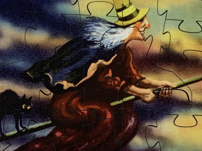 Może przedstawiać: Puzzle w stylu vintage przedstawiające wiedźmę na miotle na tle zachmurzonego nieba. Wiedźma ma na sobie ż&oacute;łty kapelusz i czerwoną suknię, a obok leci czarny kot. Widoczne są elementy układanki.