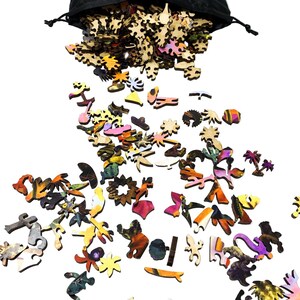 May include: A black drawstring bag spilling out wooden puzzle pieces in various shapes and colors. The pieces are scattered on a white surface, showcasing a variety of designs and hues, including orange, purple, and green.