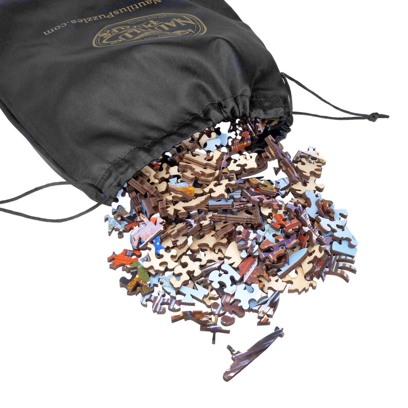 May include: A black drawstring bag with the text "nautiluspuzzles.com" is open, spilling out wooden puzzle pieces. The pieces are various shapes and colors, including brown, white, red, and blue.
