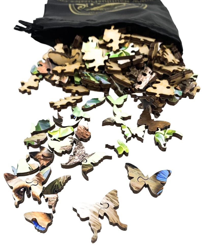 May include: A black drawstring bag spills out wooden jigsaw puzzle pieces. Many pieces are butterfly-shaped, with natural wood grain and colorful imagery. The puzzle pieces are scattered, suggesting a completed puzzle or a work in progress.