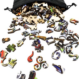 May include: A black drawstring bag spills out wooden puzzle pieces. The pieces are various shapes and sizes, with colorful images and text. The puzzle pieces are scattered on a white surface, creating a visually engaging display.