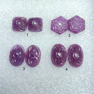 Puede incluir: Cuatro pares de piedras preciosas púrpuras talladas, cada par con un diseño diferente. Las piedras preciosas están dispuestas en filas de dos, etiquetadas del 1 al 4.