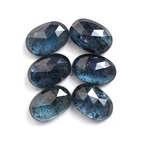 May include: Six oval-shaped blue gemstones with a faceted cut. The gemstones have a dark blue color with a slight shimmer.