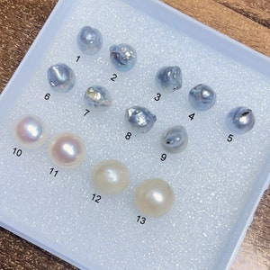 Puede incluir: Trece perlas diferentes en una bandeja de espuma blanca. Las perlas est&aacute;n numeradas del 1 al 13. Las perlas son una mezcla de blanco y azul.