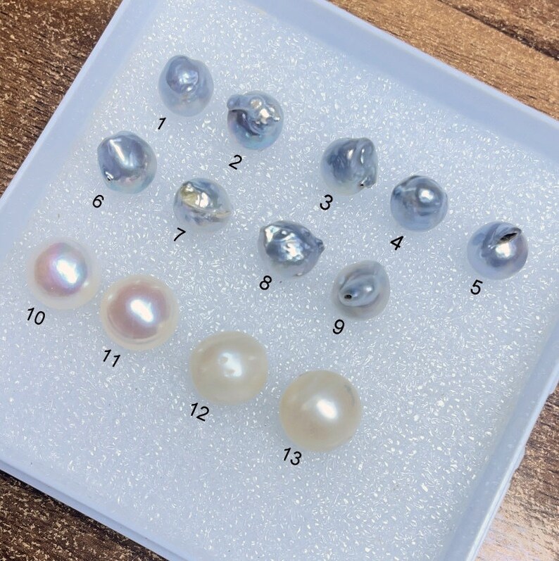 Puede incluir: Trece perlas diferentes en una bandeja de espuma blanca. Las perlas est&aacute;n numeradas del 1 al 13. Las perlas son una mezcla de blanco y azul.
