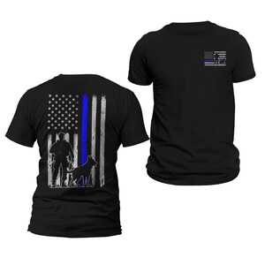 May include: Two black t-shirts with a thin blue line and an American flag design. The back of one shirt features a silhouette of a police officer and a dog. The front of the other shirt features a thin blue line and an American flag.