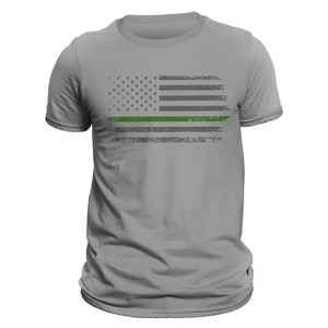 May include: A gray t-shirt with a distressed American flag design featuring a green stripe across the middle.