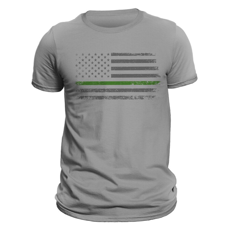 May include: A gray t-shirt with a distressed American flag design featuring a green stripe across the middle.