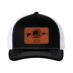 May include: Black and white trucker hat with a brown leather patch that says "2nd Amendment Going Good Guys Guns Since 1791" with an American flag and a silhouette of a rifle.