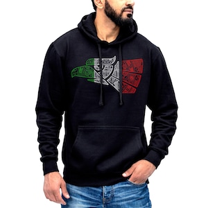 Könnte beinhalten: Schwarzer Kapuzenpullover mit einem stilisierten Adlerdesign. Der Adlerkopf ist in Grün, Weiß und Rot gefärbt. Der Pullover hat eine Vordertasche und eine Kapuze mit Kordelzug.