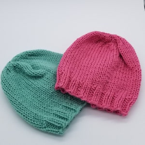 May include: Two knitted hats, one in a light green color and the other in a bright pink color.