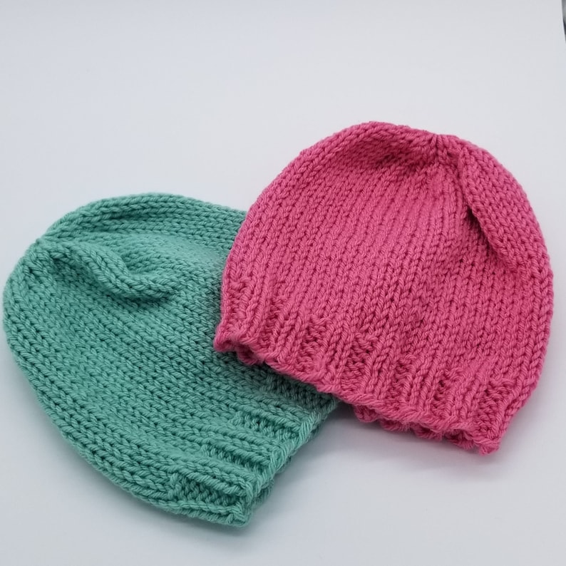 May include: Two knitted hats, one in a light green color and the other in a bright pink color.