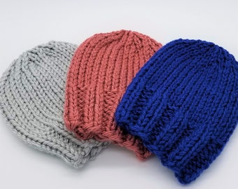 May include: Three knitted hats in different colors: gray, coral, and blue. The hats are made with a simple knit stitch and have a slouchy fit.
