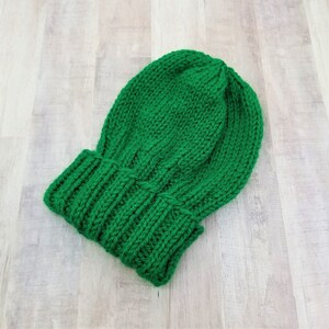 May include: A green knitted beanie hat with a ribbed brim.