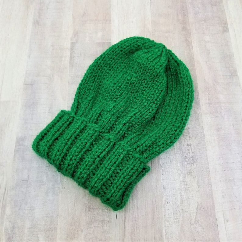 May include: A green knitted beanie hat with a ribbed brim.