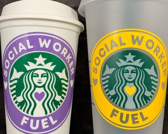 Könnte beinhalten: Zwei weiße wiederverwendbare Kaffeetassen mit einem grünen Starbucks-Logo und dem Text "SOCIAL WORKER FUEL" in Lila und Gelb. Die kleinere Tasse hat ein lilafarbenes Herz und die größere ein gelbes Herz.