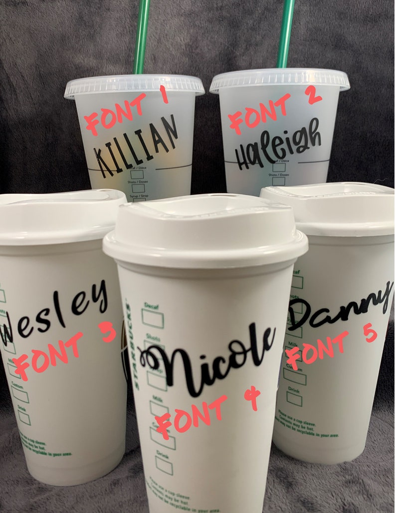 Pode incluir: Cinco copos de caf&eacute; reutiliz&aacute;veis brancos com texto preto. Os copos s&atilde;o etiquetados com nomes e estilos de fonte diferentes. Os nomes s&atilde;o Killian, Haleigh, Wesley, Nicole e Danny. Os estilos de fonte s&atilde;o etiquetados como Fonte 1, Fonte 2, Fonte 3, Fonte 4 e Fonte 5.