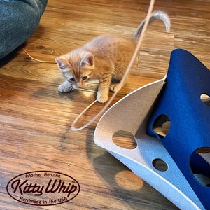 A tan kitten stalking the KittyWhip Leather® wand cat toy.