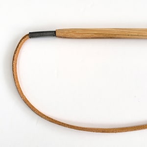 The metal spring strain relief and leather cord of the KittyWhip Plus Leather® wand cat toy displayed against a white background.