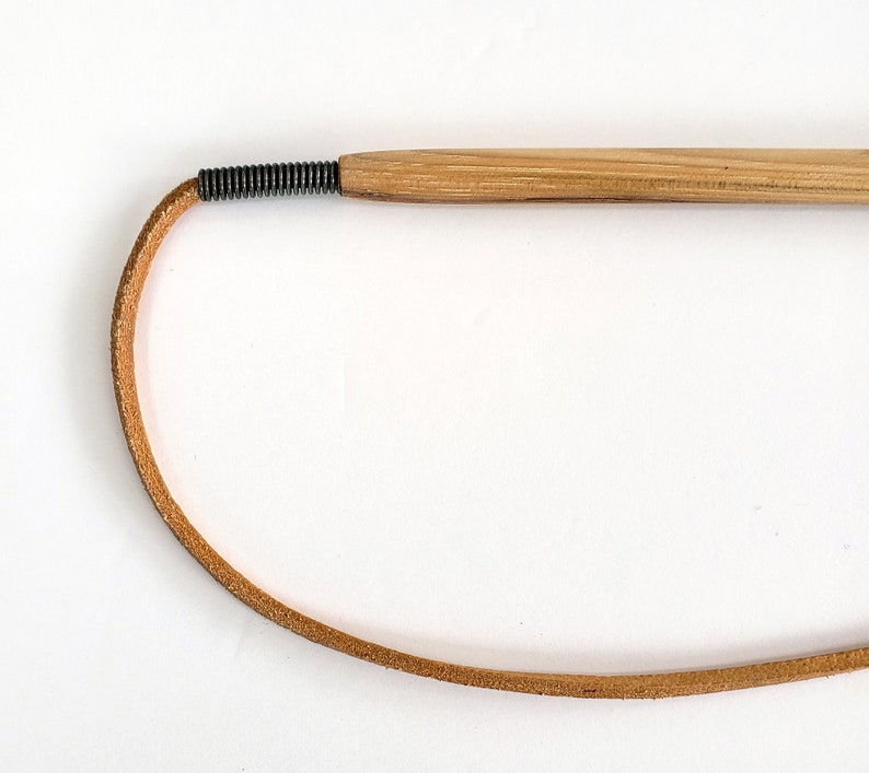 The metal spring strain relief and leather cord of the KittyWhip Plus Leather® wand cat toy displayed against a white background.