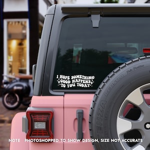 May include: A white vinyl decal applied to the rear window of a pink vehicle. The decal features the text I HOPE SOMETHING GOOD HAPPENS TO YOU TODAY in a bold, retro-style font, accented by small four-pointed star shapes surrounding the lettering.