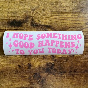 May include: A rectangular white sticker featuring the pink text I HOPE SOMETHING GOOD HAPPENS TO YOU TODAY in a wavy, retro-inspired font. The design includes small pink four-pointed star icons on the left and right sides of the text.