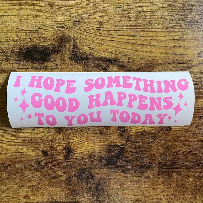 May include: A rectangular white sticker featuring the pink text I HOPE SOMETHING GOOD HAPPENS TO YOU TODAY in a wavy, retro-inspired font. The design includes small pink four-pointed star icons on the left and right sides of the text.