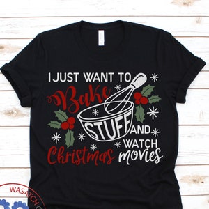 Könnte beinhalten: Schwarzes T-Shirt mit dem Text "I just want to bake stuff and watch Christmas movies" in Weiß und Rot. Das Design zeigt eine Schüssel, einen Schneebesen, Stechpalmen und Schneeflocken, für Weihnachten.