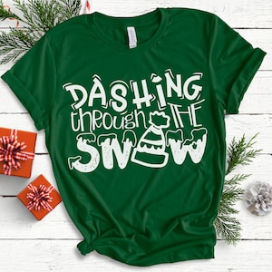 May include: Green t-shirt with white text that reads "Dashing through the snow" with a white cartoon snowman wearing a hat.