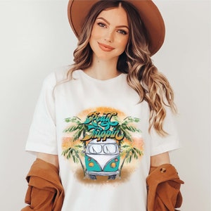 May include: White t-shirt with a graphic of a teal and white vintage van with palm trees and the text "Road Trippin'" in a colorful font.
