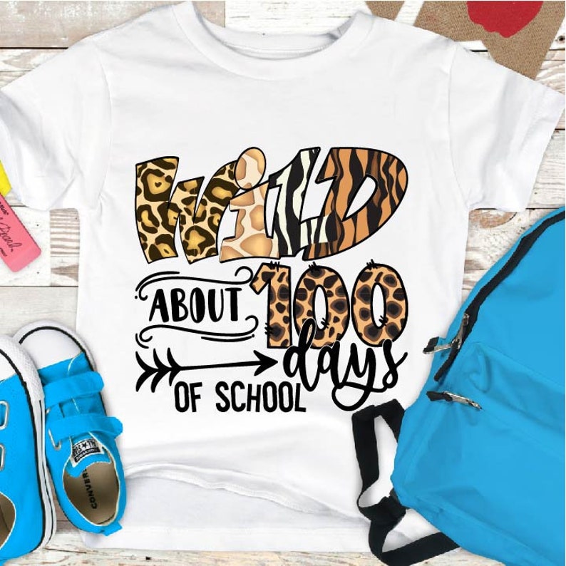 May include: White t-shirt with a graphic that says "Wild About 100 Days of School". The graphic is made up of animal print designs in brown, black, and white.