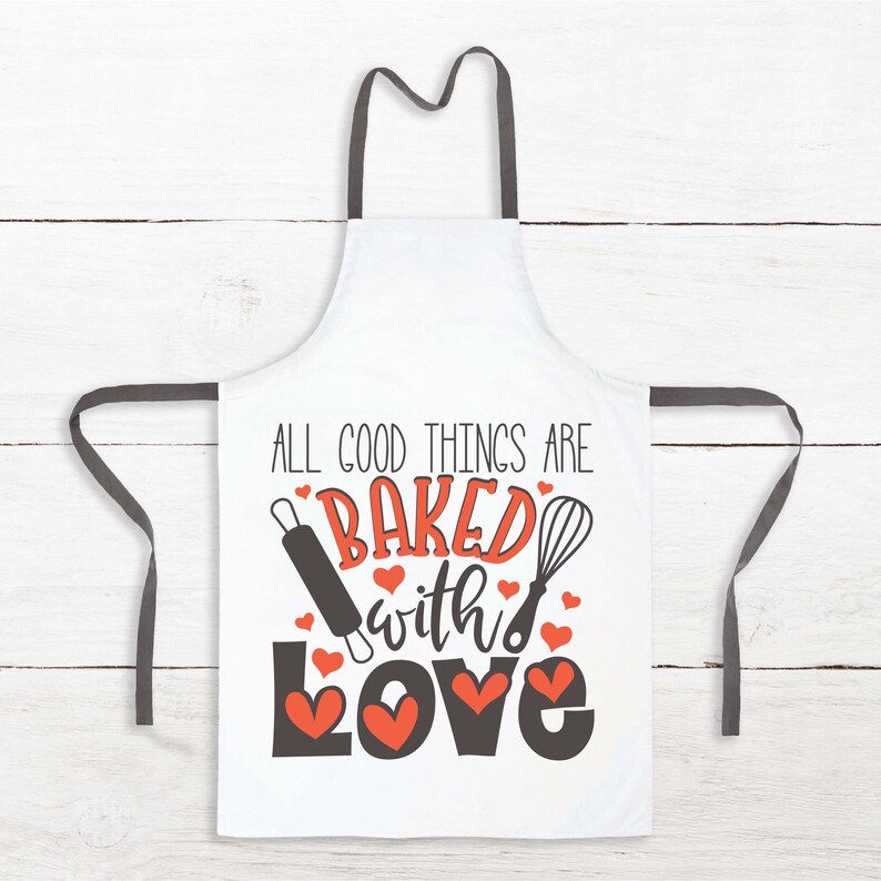 Peut inclure: Tablier blanc avec des bretelles noires et le texte "All good things are baked with love" en noir avec un motif de c&oelig;ur rouge. Un rouleau &agrave; p&acirc;tisserie et un fouet sont illustr&eacute;s de chaque c&ocirc;t&eacute; du texte.