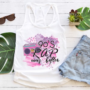 Op de afbeelding: Een wit tanktop met een roze en paarse grafische print met een ghettoblaster en de tekst "90's Rap was better".
