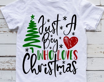 Könnte beinhalten: Weißes T-Shirt mit einem grünen Weihnachtsbaum, einem roten Herzen und dem Text "Just a Boy Who Loves Christmas" in Schwarz.