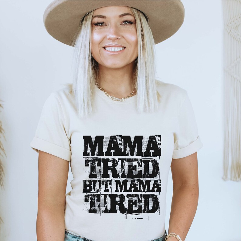 Pu&ograve; includere: Una maglietta beige con una grafica nera che recita "Mama Tried But Mama Tired".