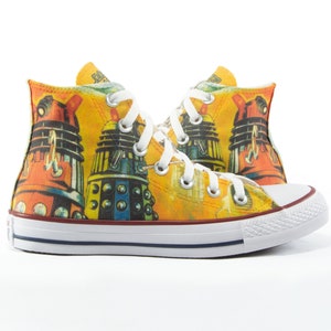 Op de afbeelding: Gele Converse sneakers met hoge schacht en een grafische print van Daleks uit Doctor Who.