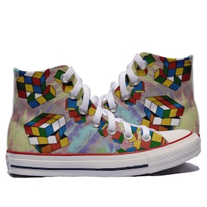 Könnte beinhalten: Hochwertige Canvas-Sneaker mit einem Batik-Hintergrund und einem bunten Rubik's Cube-Muster. Die Schuhe haben weiße Schnürsenkel und eine weiße Gummisohle.