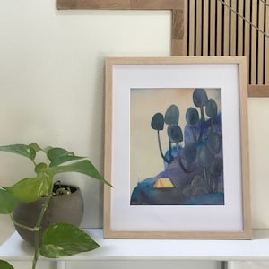 May include: A framed watercolor painting of a forest scene with a small yellow tent in the foreground. The trees are stylized and have a blue-grey color. The background is a gradient of blue and purple.