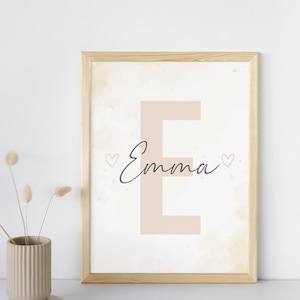 Könnte beinhalten: Ein rechteckiger Wandkunstdruck in einem hellen Holzrahmen mit einem großen, blassrosa Buchstaben E im Hintergrund, über den der Name Emma in schwarzer Schreibschrift geschrieben ist, akzentuiert durch zwei kleine, handgezeichnete Herzen.