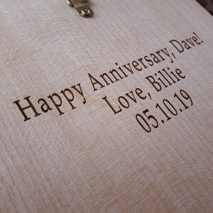 May include: A close-up of a wooden surface with the text "Happy Anniversary, Dave! Love, Billie 05.10.19" engraved on it.