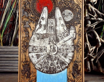 May include: A wood-carved wall art piece featuring a vintage-style illustration of the Millennium Falcon spaceship from Star Wars. The artwork is framed in a dark wood frame and has a blue background.