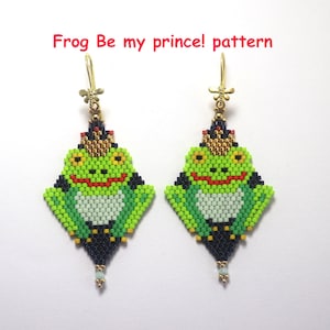 Könnte beinhalten: Ein Paar Perlenohrringe in Form eines Frosches. Die Ohrringe sind hauptsächlich grün mit schwarzen, roten und goldenen Akzenten. Der Text "Frog Be my prince! pattern" steht in Rot über den Ohrringen.