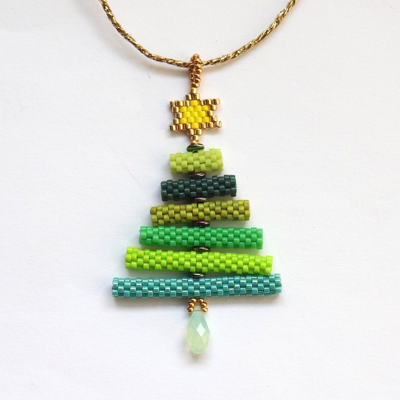 May include: A beaded Christmas tree pendant necklace. The tree is made of various shades of green beads, with a yellow star at the top and a pear-shaped green bead at the bottom. The chain is gold-coloured.