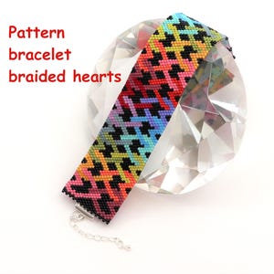 Peut inclure: Un bracelet en perles coloré avec un motif de cœur tressé. Le bracelet est noir avec des cœurs arc-en-ciel.