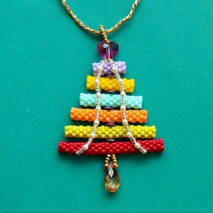 May include: A vibrant beaded Christmas tree pendant necklace. The tree is constructed from stacked, cylindrical beads in red, yellow, orange, turquoise, lavender, and a heart-shaped purple bead. A gold chain and a teardrop pendant complete the design.