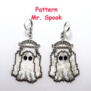 Könnte beinhalten: Ein Paar Geisterohrringe aus Perlen. Jeder Ohrring zeigt ein weißes Geisterdesign mit schwarzen Augen und einem silberfarbenen Bügel. Der Text "Pattern Mr. Spook" steht in Rot über den Ohrringen.