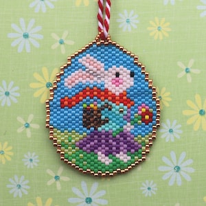May include: A round, beaded ornament featuring a white bunny holding a basket of colourful eggs. The bunny is wearing a red and orange scarf and is surrounded by green and purple beads.